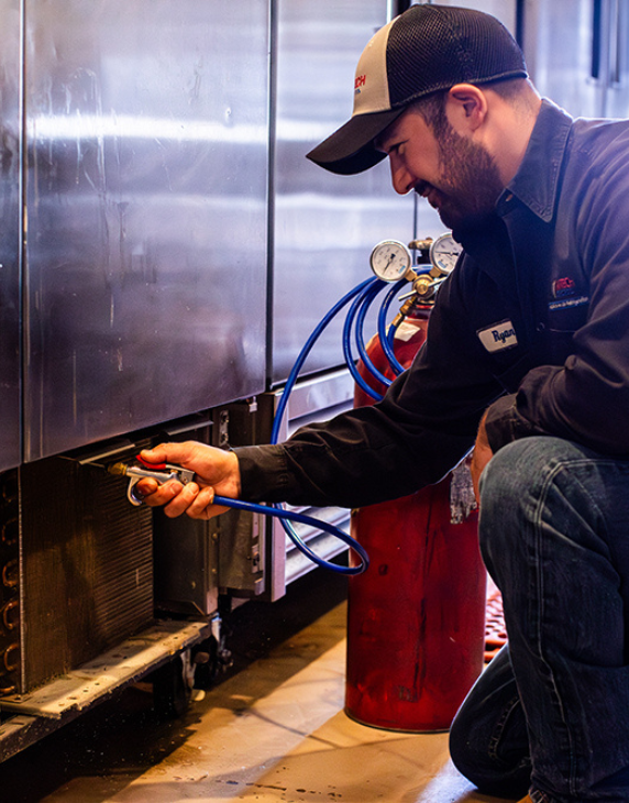 Image of a service tech performing refrigeration maintenance